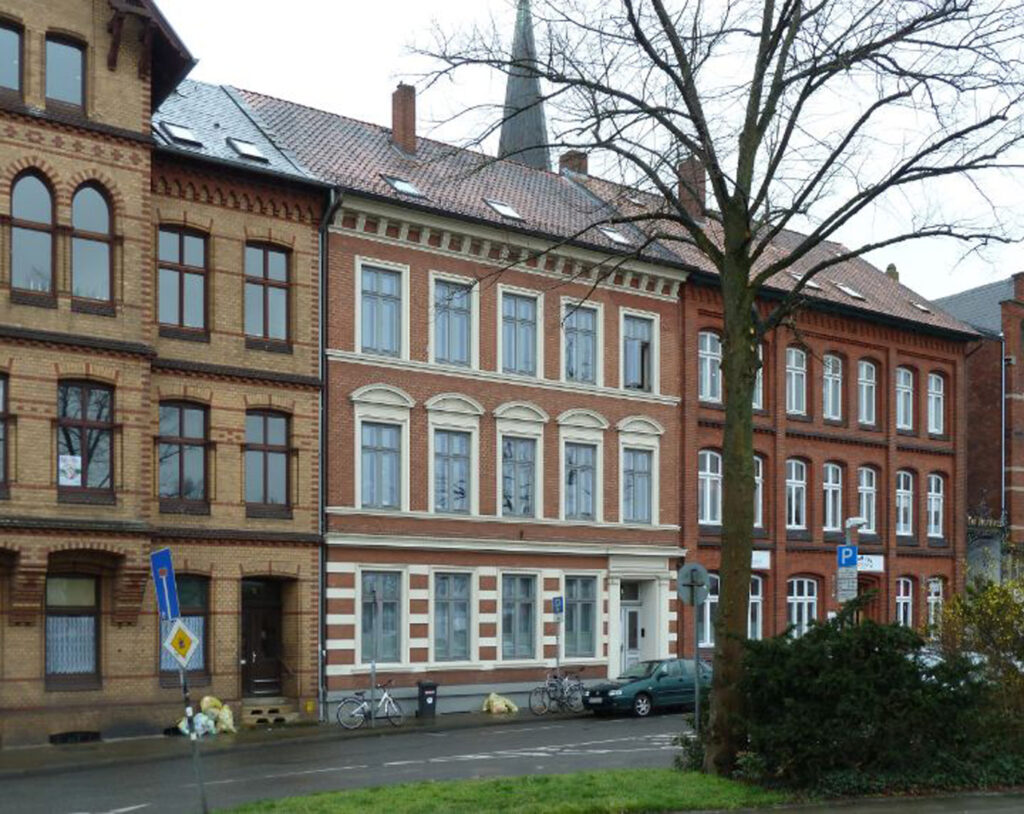 Mehrfamilienhaus von 1893 in Lüneburg mit Fassade im Gründerzeitstil, nach Brandschaden vor geplanter Sanierung abgebildet.